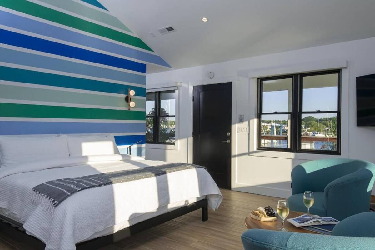 Un dormitorio moderno con una cama grande, vista al mar y un balcón con una silla.