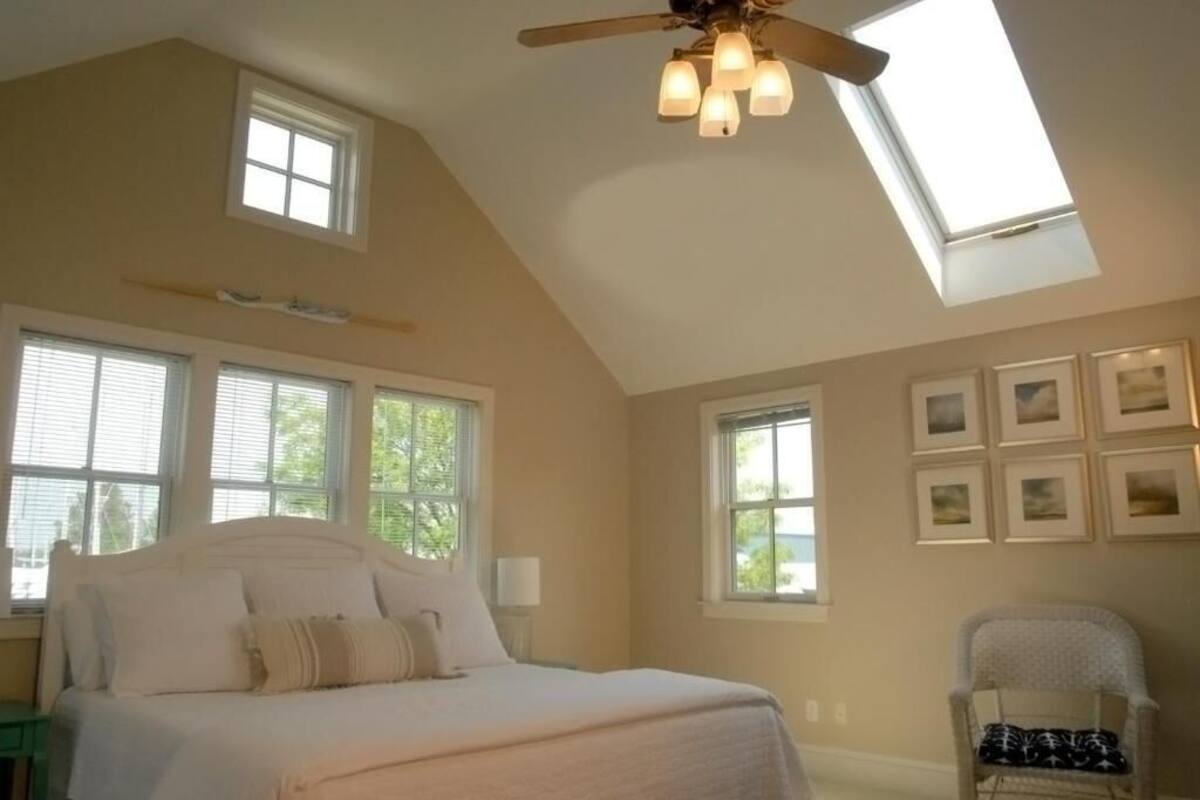 Un dormitorio con cama, ventilador de techo y varias ventanas.