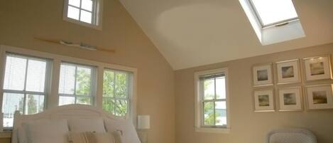 Une chambre à coucher avec un lit, un ventilateur de plafond et plusieurs fenêtres.