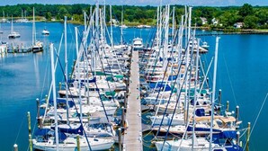 A marina with numerous sailboats docked in a row, connected by a wooden walkway. - Inn at Haven Harbour (Rock Hall)