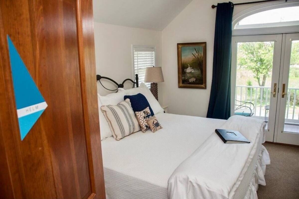 Un dormitorio con cama, lámpara, un cuadro y vistas al exterior.