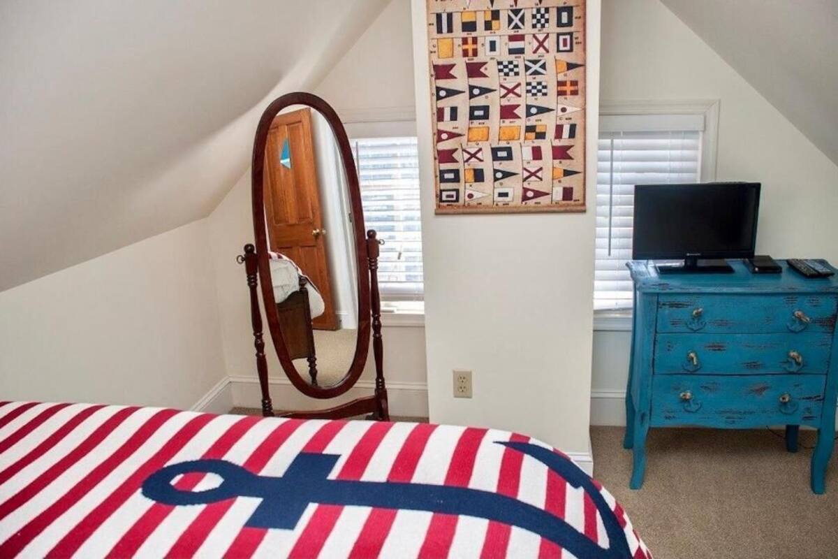 Un dormitorio con cama, cómoda, espejo y colcha.
