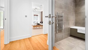 Une salle de bain moderne équipée d’une douche, d’un porte-serviettes et de toilettes apparentes.