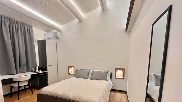A modern bedroom with a bed, bedside tables, a desk, and a chair. - Dimore Diffuse R H (Rende)
