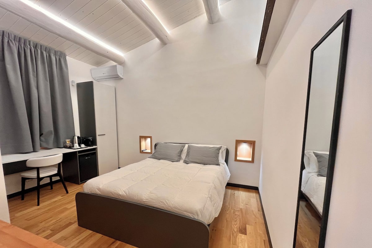 A modern bedroom with a bed, bedside tables, a desk, and a chair.