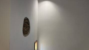 A room with a stone accent wall, a bed with a headboard, and a ceiling light.