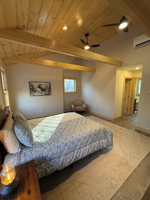 A bedroom with a bed, a ceiling fan, a window, and a door.