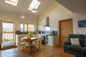 A compact kitchen with a dining area, a sofa, and a view of the outside.