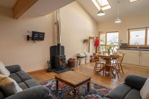 Una sala de estar acogedora con chimenea, un comedor y una cocina con ventanas amplias.