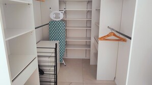 A walk-in closet with multiple shelves and hanging space, featuring a star-patterned garment and a black hanger. - Mimosa house, T2 48 M2, quiet location with unobstructed view, 9min from beaches (Bormes-les-Mimosas)