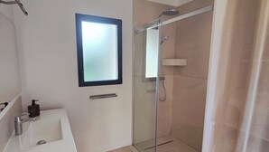 A modern bathroom with a glass-enclosed shower, a white sink with a wooden vanity, and a frosted glass mirror. - Mimosa house, T2 48 M2, quiet location with unobstructed view, 9min from beaches (Bormes-les-Mimosas)