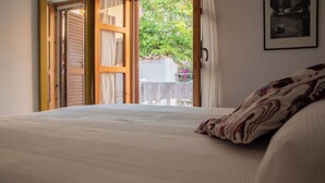 Une chambre avec un grand lit, une fenêtre ouverte et une vue sur un jardin.