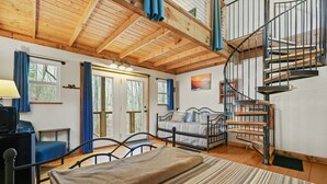 A cozy room with a bed, a desk, and a spiral staircase. - Fairytale SQUIRREL'S NEST cabin at Mulberry Gap in Ellijay! (Ellijay)