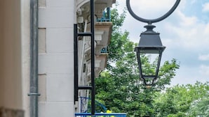 A white building with a blue wrought iron balcony railing and a black street lamp.