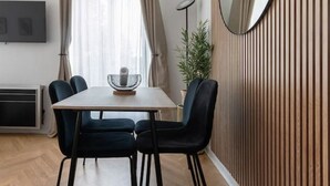 A modern dining area with a wooden dining table, black chairs, and a large mirror on the wall.