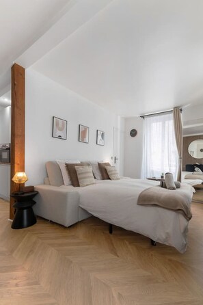 Un dormitorio moderno con una cama grande, una mesita de noche con lámpara y estructura de vigas de madera.