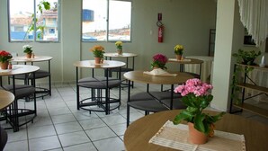 Un comedor con mesas redondas, sillas y plantas en macetas.