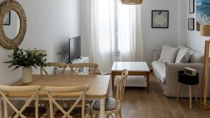 Moderni olohuone, jossa on puinen ruokapöytä, valkoinen sohva ja televisio.