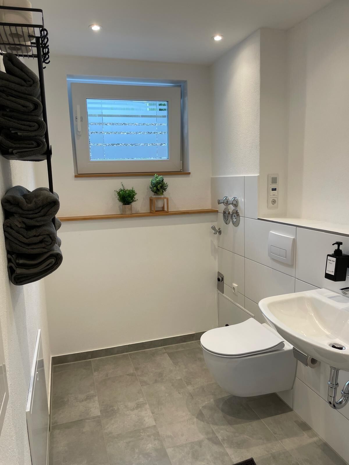 A modern bathroom with a toilet, sink, and towel rack.