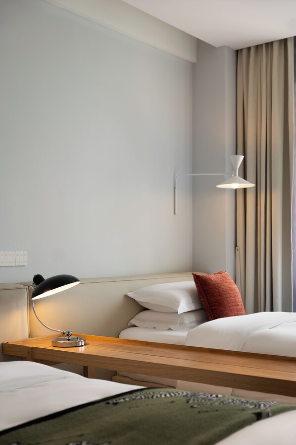 Una habitación de hotel con cama, mesita de noche, lámpara y cortinas.