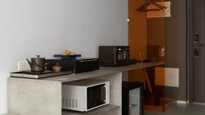 Una cocina moderna equipada con microondas, hervidor y un refrigerador compacto.