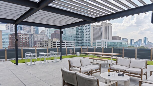 A rooftop terrace with outdoor seating, a view of the city skyline, and a covered area with a pergola. - Sosuite at The Onyx - Museum District (Philadelphia)