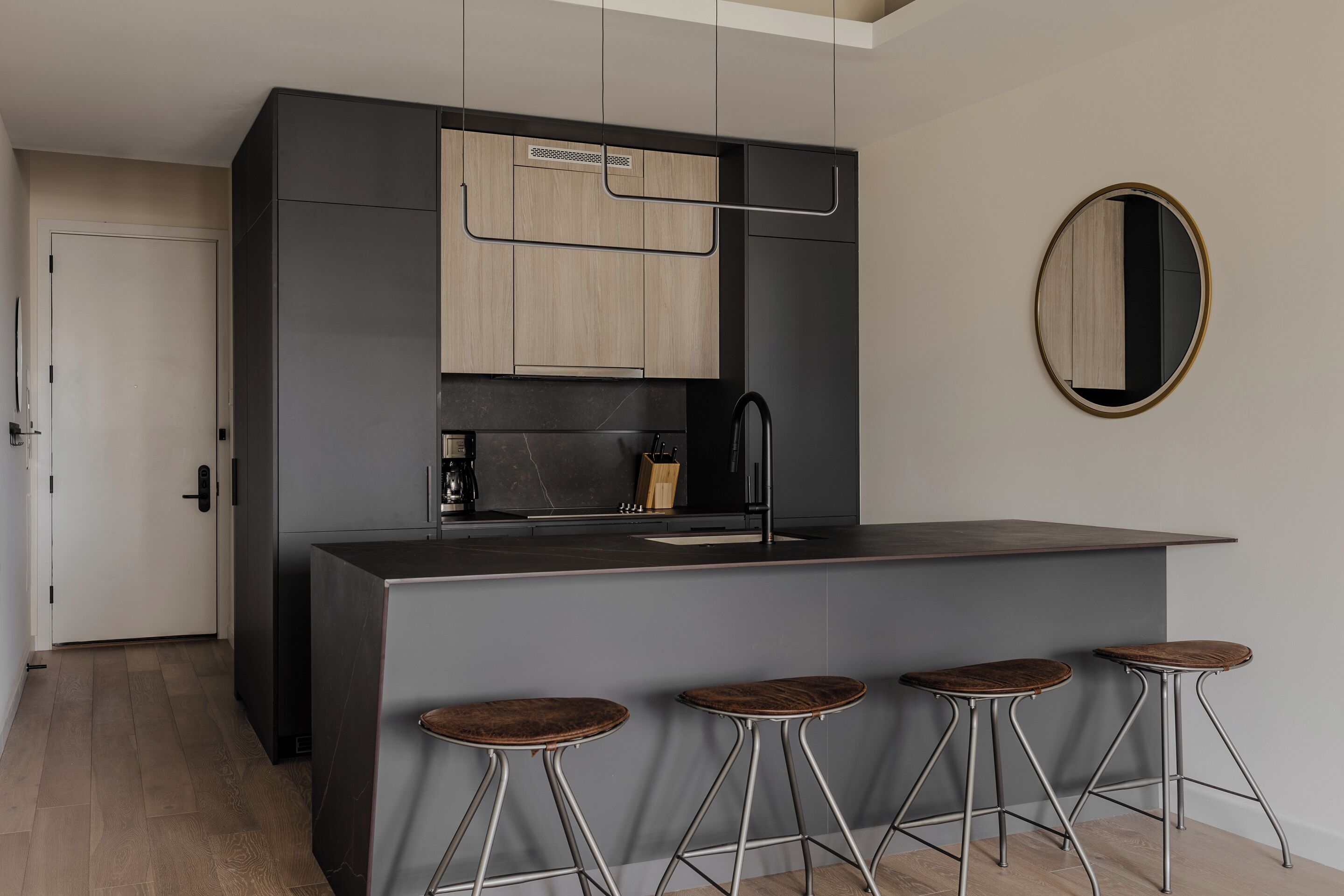Una cocina moderna con armarios oscuros, una isla central y taburetes de bar.