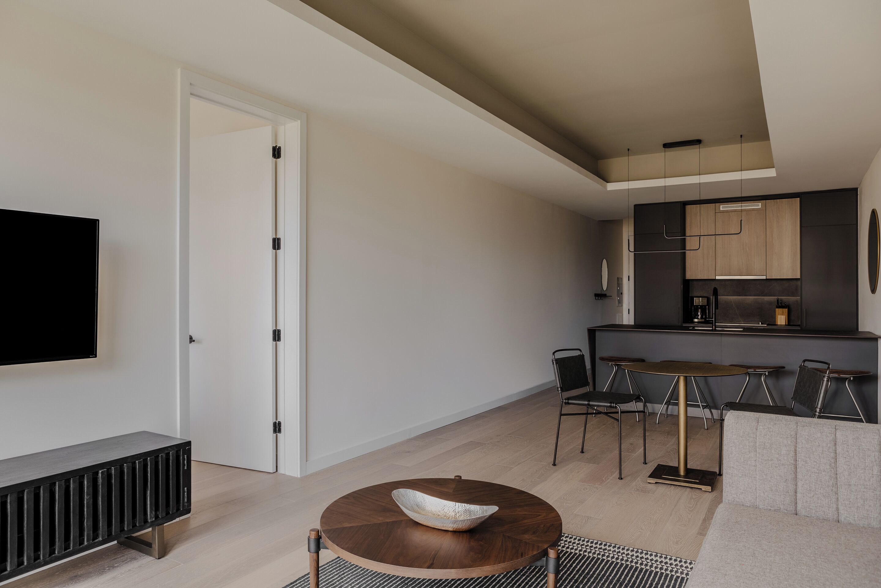 A modern living room with a round coffee table, a sofa, a TV, and a dining area with chairs and a table.