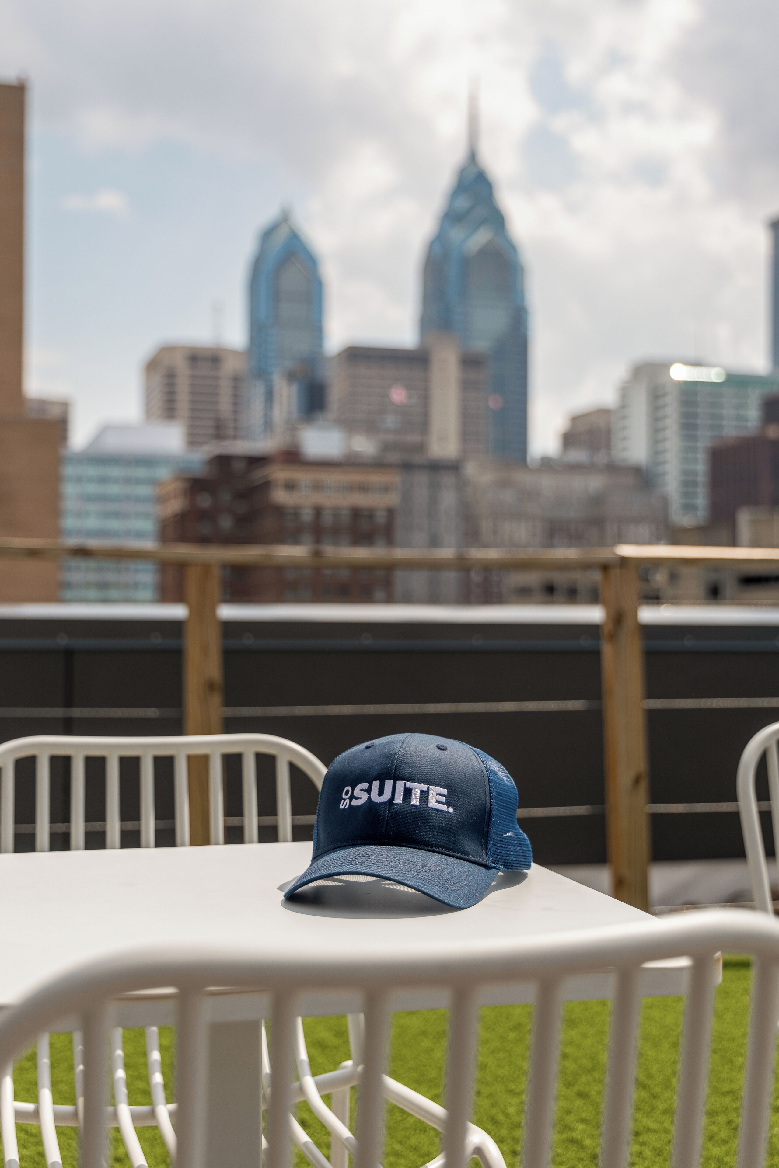 Une table blanche surmontée d’un plateau bleu portant l’inscription « SUITE », placée devant un panorama urbain avec des bâtiments imposants en arrière-plan.