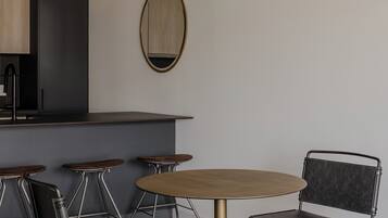 A modern kitchen with a central island, bar stools, and a round table with chairs.