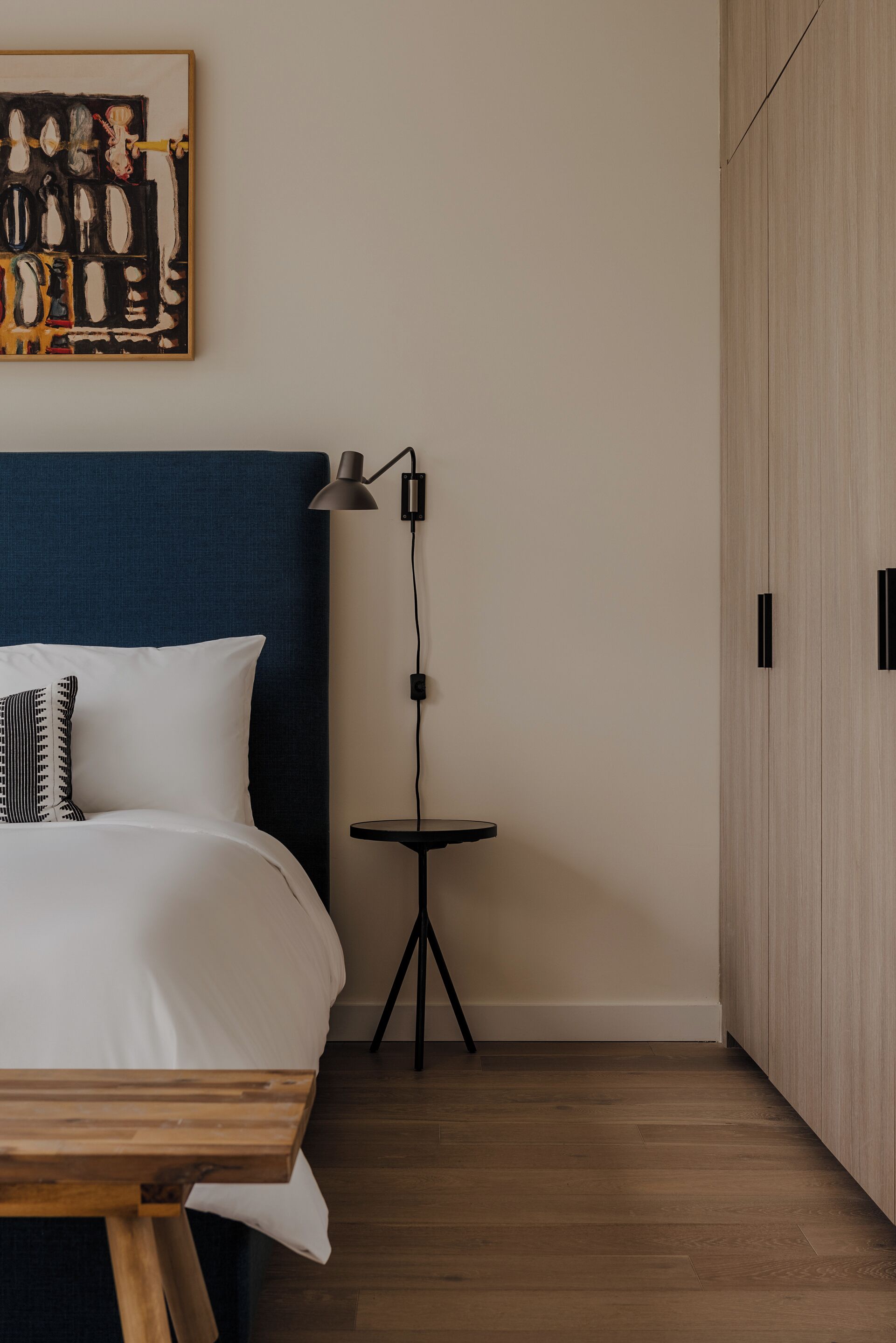 Ein ordentlich eingerichtetes Schlafzimmer mit Bett, Nachttisch, Lampe und Kleiderschrank.