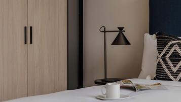 A neatly arranged bedroom with a bed, a bedside table with a lamp, and a wardrobe.