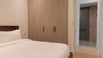 Un dormitorio con una cama grande, un armario de madera y un baño visible a través de una puerta abierta.