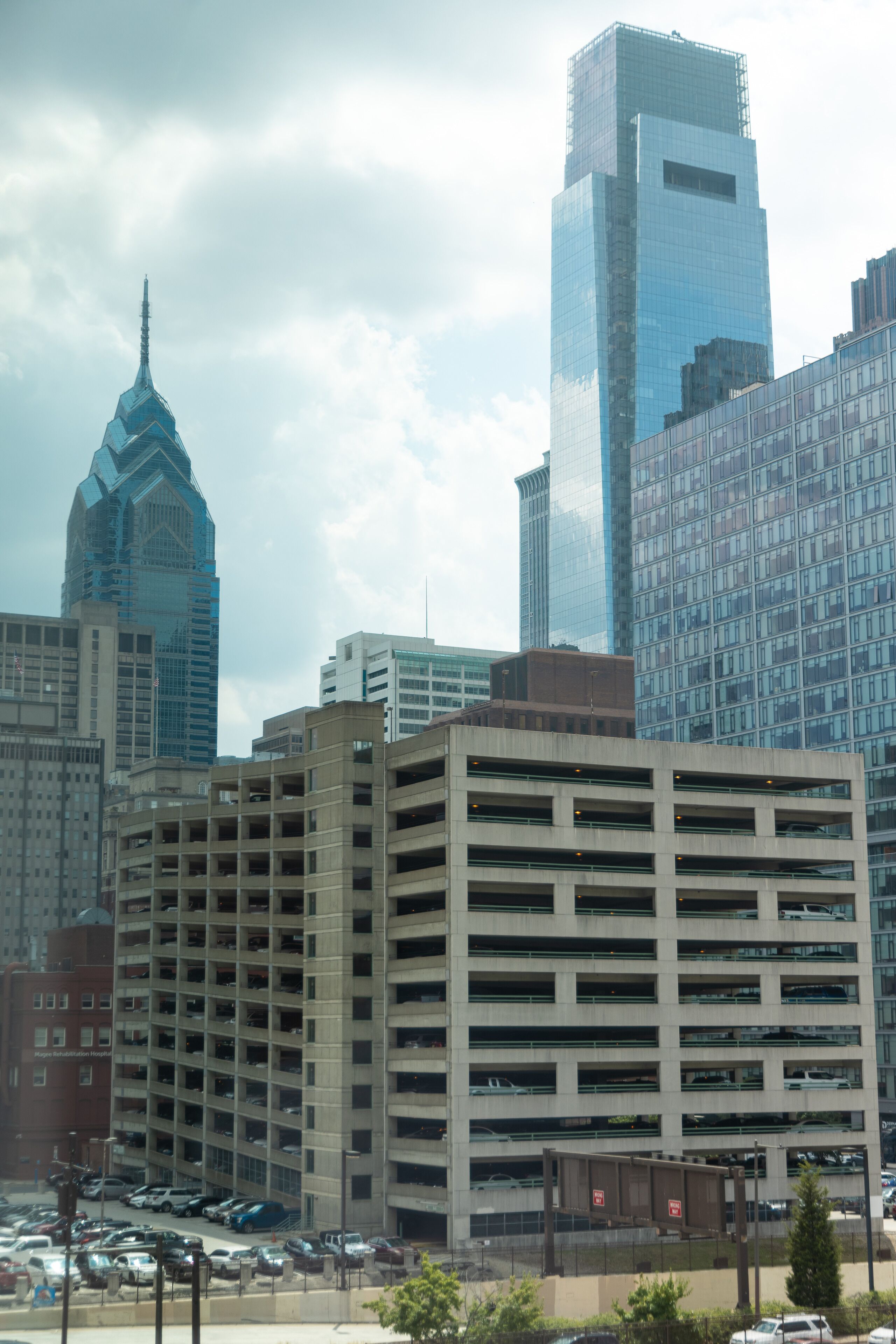A multi-story parking garage with a grid of parking spaces, surrounded by modern high-rise buildings.