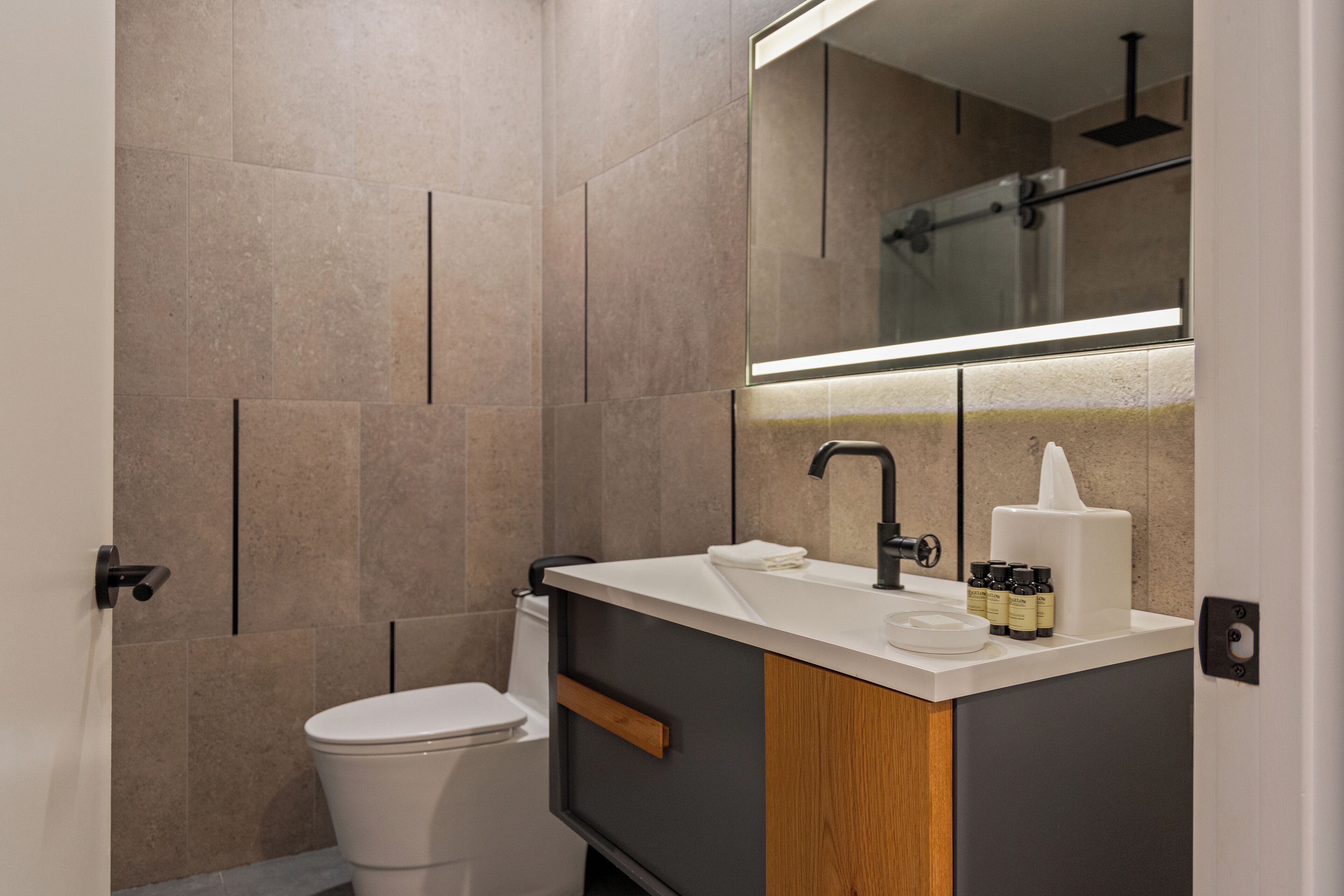 Un baño moderno con inodoro, lavamanos y espejo.
