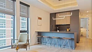 A modern kitchen with a bar area, large windows, and a seating area with a table and chairs. - Sosuite at The Onyx - Museum District (Philadelphia)
