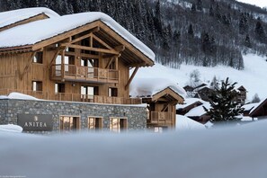 A wooden chalet with a stone foundation, a balcony, and a sign reading "ANITEA". - MGM Hôtels et Résidences - Residence Anitea (Les Avanchers-Valmorel)