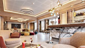 Un vaste espace de détente avec des sièges confortables, un bar doté d’un comptoir en marbre et un design de plafond moderne.
