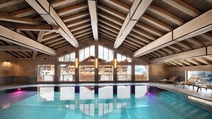Une grande piscine intérieure avec des poutres en bois et de grandes fenêtres.