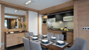 Una cocina moderna con armarios de madera, electrodomésticos de acero inoxidable y un comedor con mesa de madera y sillas estampadas.