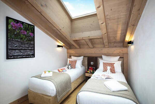 A room with two single beds, wooden beams, a skylight, and a framed picture on the wall. - MGM Hôtels et Résidences - Residence Anitea (Les Avanchers-Valmorel)