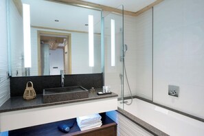 Un baño moderno con un espejo grande, un lavamanos y una ducha.