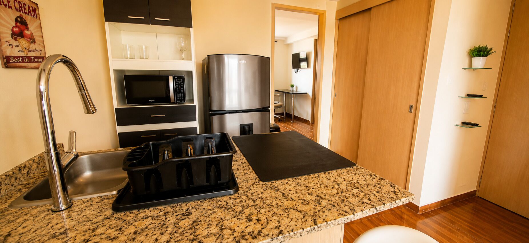 Una cocina con encimera de granito, electrodomésticos de acero inoxidable, un juego de cuchillos negros y un microondas.