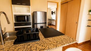 Una cocina con encimera de granito, electrodomésticos de acero inoxidable, un juego de cuchillos negros y un microondas.