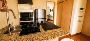 Una cocina con encimera de granito, electrodomésticos de acero inoxidable, un juego de cuchillos negros y un microondas.