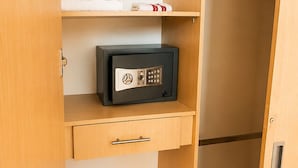 Ein Holzschrank mit Safe, einem gefalteten Handtuch und einer Kleiderstange.