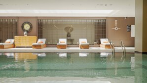 Une piscine avec des chaises longues et un meuble en bois.