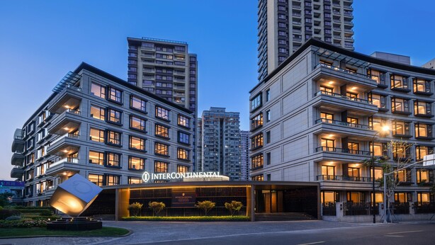 Un hôtel moderne composé de plusieurs immeubles de grande hauteur, doté d’une entrée bien éclairée et d’un espace paysager aménagé à l’avant.