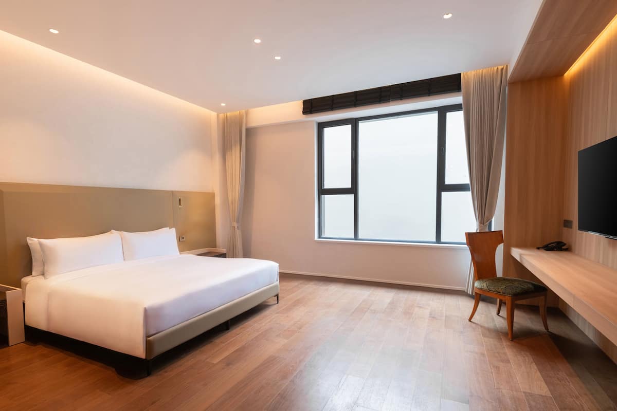 Une chambre d’hôtel moderne équipée d’un grand lit, d’un bureau, d’une chaise et d’un téléviseur.