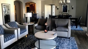 A modern living room with a sofa, armchairs, a coffee table, and a dining area in the background. - Wyndham Oceanside Pier Resort - 3 Bedroom Ocean View Presidential Suite - Ocean (Oceanside)